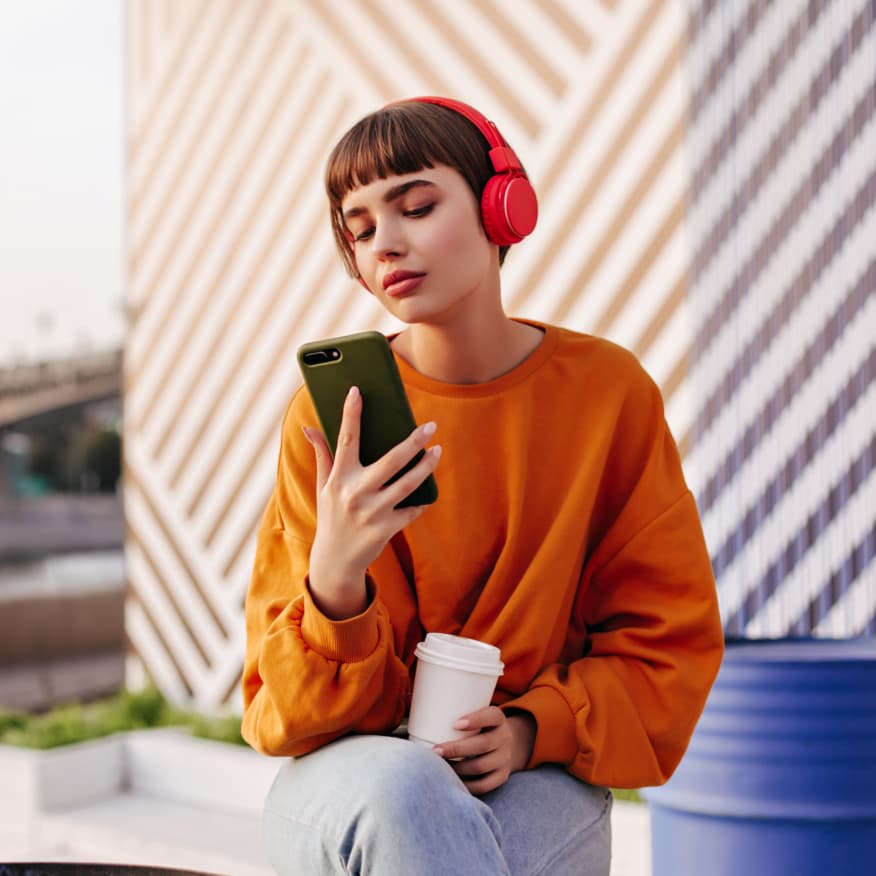 Artista usando fones vermelhos enquanto revisa conteúdo social no celular.